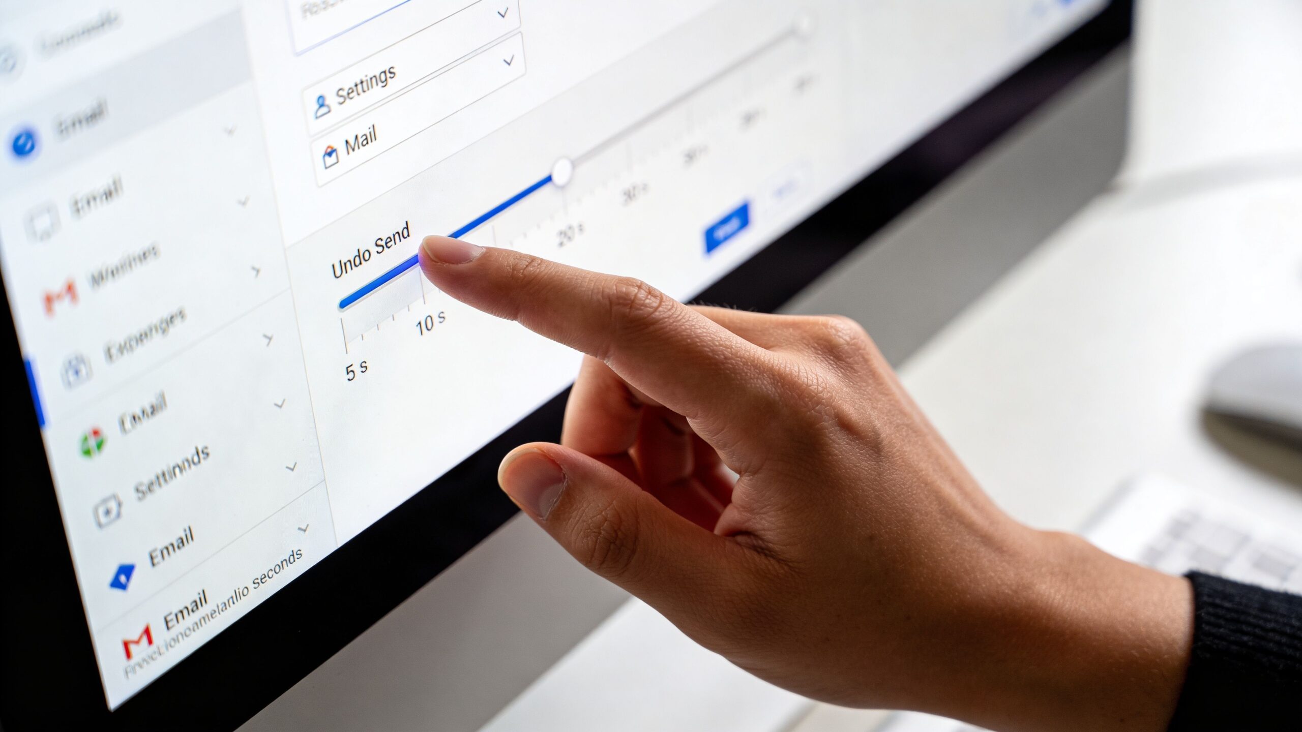 A close-up view of a person using their finger to adjust the undo send timer on a computer screen.